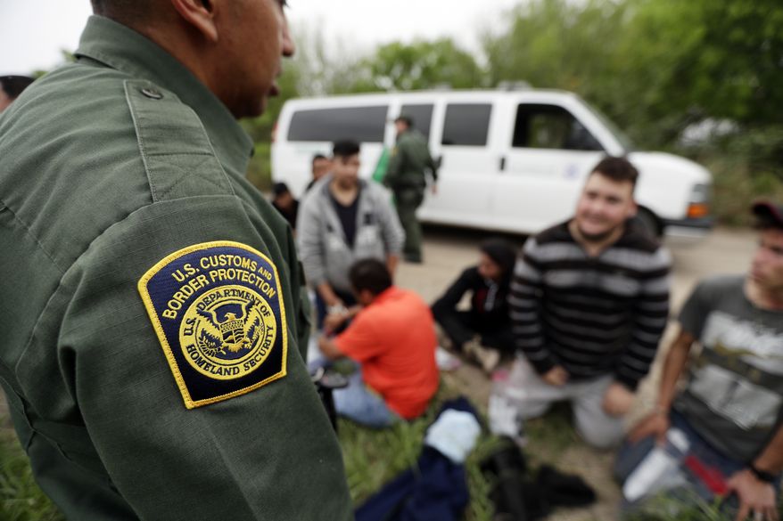 In this Thursday, March 14, 2019, photo, a Border Patrol agent talks with a group suspected of having entered the U.S. illegally near McAllen, Texas. While many adults crossing the border on their own in South Texas try to flee agents, most migrant parents and children wait to surrender so they can be processed and released into the United States. (AP Photo/Eric Gay)