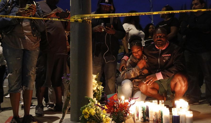 Haitian-French actor Jimmy Jean-Louis and his daughter Jasmin, 16, gather around candles set up across from the clothing store of rapper Nipsey Hussle in Los Angeles, Sunday, March 31, 2019. Hussle, the skilled and respected West Coast rapper who had a decade-long success with mixtapes but hit new heights with his Grammy-nominated major-label debut album in 2018, has died. He was 33. (AP Photo/Damian Dovarganes)