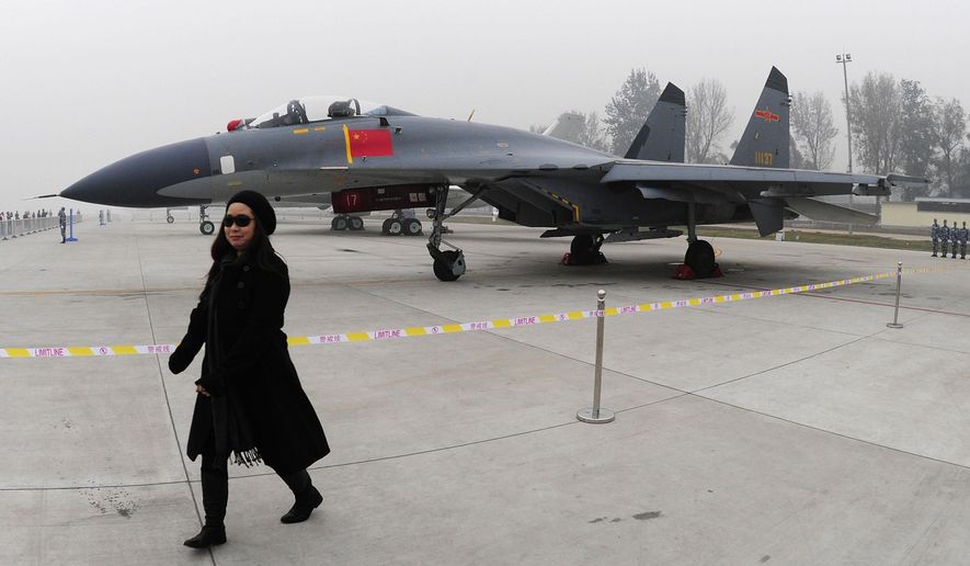 FILE - In this Nov. 8, 2009, file photo, a woman walks near a Chinese People&#39;s Liberation Army Air Force&#39;s J-11 fighter jet displayed for the Air Force&#39;s 60th anniversary at an airport in Beijing, China. Taiwan says its planes warned off Chinese military aircraft that crossed the center line in the Taiwan Strait, calling China’s move a provocation that seeks to alter the status quo in the waterway dividing the island from mainland China.(AP Photo, File)