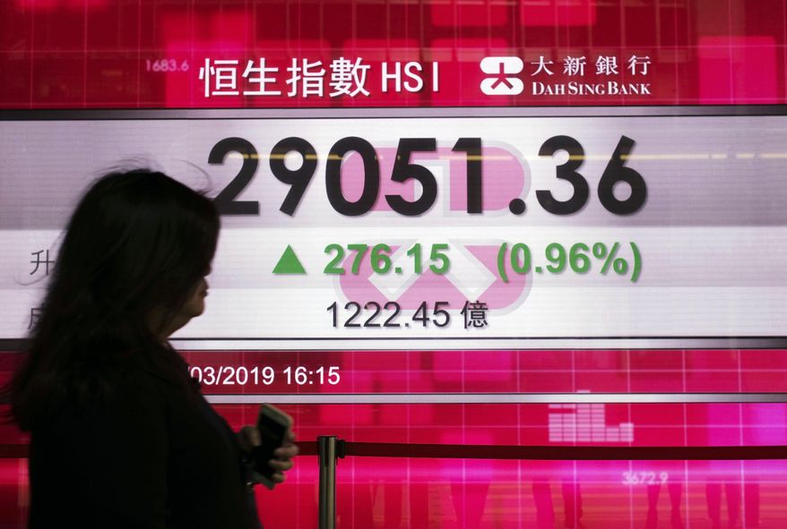 A woman walks past an electronic board showing Hong Kong share index outside a local bank in Hong Kong, Monday, April 1, 2019. Shares have surged in Asia following a bullish Friday on Wall Street, where the benchmark S & P 500 logged its biggest quarterly gain in nearly a decade. (AP Photo/Vincent Yu)