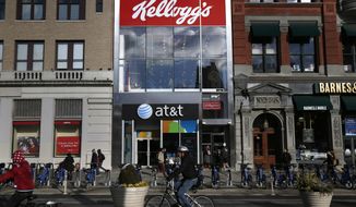 FILE- In this Dec. 14, 2017, file photo people bike and walk by Kellogg&#39;s NYC Cafe at Union Square in New York. Kellogg is selling its iconic Keebler cookie brand and other sweet snacks businesses to Ferrero for $1.3 billion. (AP Photo/Seth Wenig, File)