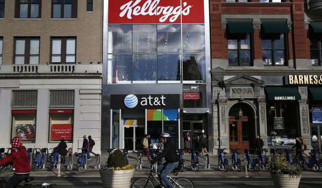 FILE- In this Dec. 14, 2017, file photo people bike and walk by Kellogg&#x27;s NYC Cafe at Union Square in New York. Kellogg is selling its iconic Keebler cookie brand and other sweet snacks businesses to Ferrero for $1.3 billion. (AP Photo/Seth Wenig, File)
