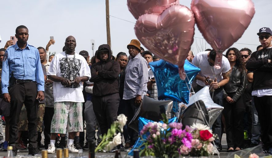 Fans of rapper Nipsey Hussle appear at a makeshift memorial in the parking lot of Hussle's Marathon Clothing store in Los Angeles, Monday, April 1, 2019. Hussle was killed in a shooting outside the clothing store on Sunday. (AP Photo/Ringo H.W. Chiu)