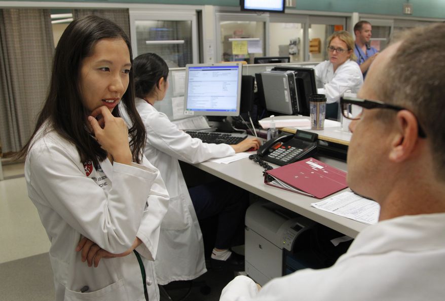 In this Tuesday, Aug. 14, 2012, file photo, Leana Wen, of Boston, left, who is doing her medical residency in emergency medicine at Harvard-affiliated Brigham and Women's Hospital and Massachusetts General Hospital, speaks with Josh Kosowsky, clinical director of emergency medicine, right, in the emergency department at Brigham and Women's Hospital, in Boston. Wen chose emergency medicine because the hours are more flexible than those of primary care physicians. (AP Photo/Steven Senne) ** FILE **