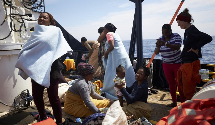 Migrants stand on the dock of the Sea-Watch rescue ship after being rescued in the waters off Libya Wednesday, April 3, 2019. The German humanitarian group Sea-Watch says the ship it operates in the central Mediterranean Sea has rescued 64 migrants in waters off Libya. Sea-Watch wrote Wednesday on Twitter that the people brought to safety from a rubber dinghy included 10 women, five children and a newborn baby. The group said it carried out the rescue off the coast of Zuwarah after Libyan authorities couldn't be reached. Sea-Watch is asking Italy or Malta to open a port to the rescue ship, the Alan Kurdi. (Fabian Heinz/Sea-eye.org via AP)