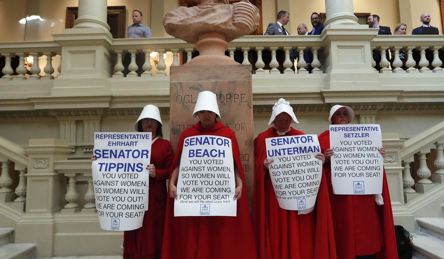Women hold signs to protest HB 481 at the state Capitol, Tuesday, April 2, 2019, in Atlanta. HB 481, which would ban most abortions after a fetal heart beat is detected, has past both the House and the Senate and awaits a signature from Gov. Brian Kemp. (AP Photo/John Bazemore)