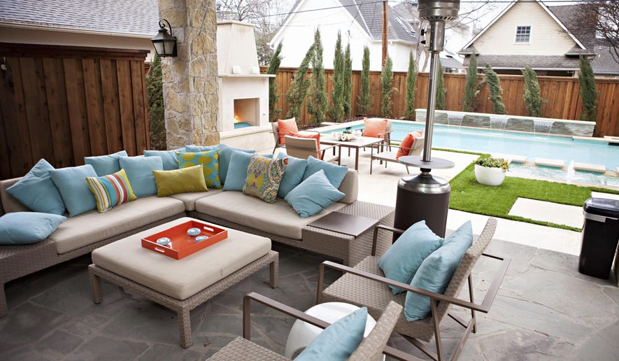 This undated photo shows an outdoor space at a home in Texas designed by Abbe Fenimore, founder of Studio Ten 25. With the addition of an outdoor fireplace and a standing space heater, a backyard can be focused on the swimming pool during the summer but be enjoyed even in cooler weather. (Melanie Johnson Photography/Abbe Fenimore via AP)