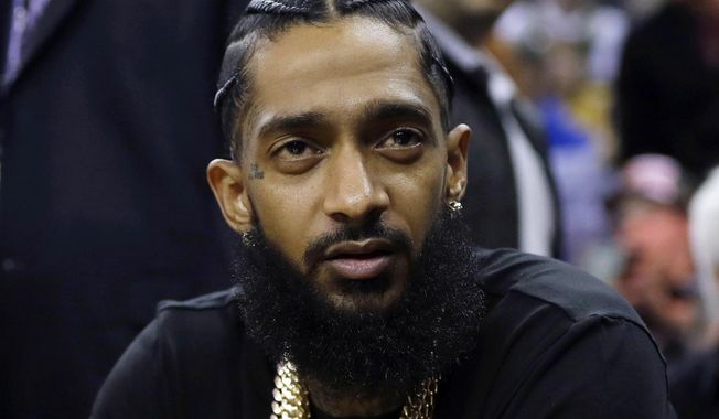 FILE - This March 29, 2018 file photo shows rapper Nipsey Hussle at an NBA basketball game between the Golden State Warriors and the Milwaukee Bucks in Oakland, Calif. Hussle was shot and killed Sunday, March 31, 2019 outside of his clothing store in Los Angeles. (AP Photo/Marcio Jose Sanchez, File)