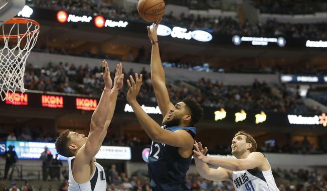 Minnesota Timberwolves center Karl-Anthony Towns (32) shoots against Dallas Mavericks defenders Dwight Powell (7) and Dirk Nowitzki (41) during the first half of an NBA basketball game in Dallas, Wednesday, April 3, 2019. (AP Photo/LM Otero)