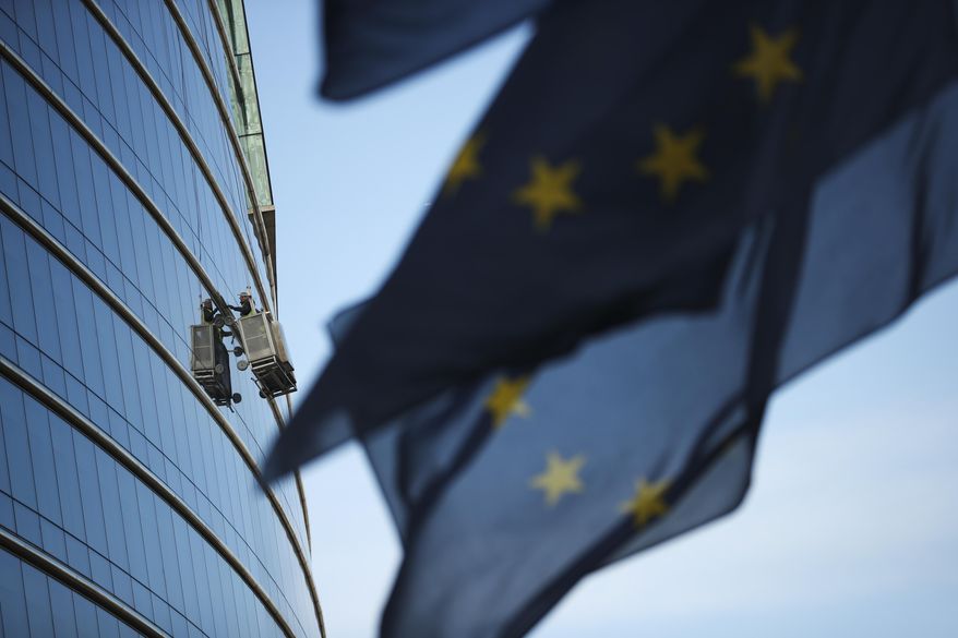 Window cleaners work on a building at the European Union headquarters area in Brussels, Thursday, April 4, 2019. The U.K. has just nine days, until April 12, to approve a divorce deal, come up with a new plan or crash out of the 28-nation bloc without a deal, causing huge disruption for people and businesses in Britain and the EU. (AP Photo/Francisco Seco)