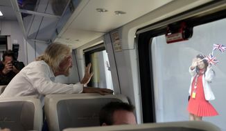 An employee holding British flags waves as Richard Branson, of Virgin Group, left, departs on a Brightline train bound for Miami, Thursday, April 4, 2019, in West Palm Beach, Fla. The state&#39;s Brightline passenger trains are being renamed Virgin Trains USA after Branson invested in the new fast-rail project that is scheduled to connect Miami with Orlando. (AP Photo/Lynne Sladky)