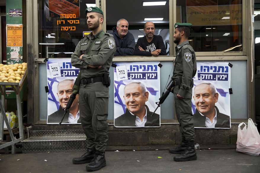 In this Tuesday, April 2, 2019, file photo, Israeli border police officers stand guard next to posters depicting Israeli Prime Minister Benjamin Netanyahu at the Ha'tikva market in Tel Aviv, Israel. As Israel prepares to hold a national election next week, experts say it is vulnerable to the kind of foreign hacks and cyber campaigns that have disrupted the political process in other countries. (AP Photo/Oded Balilty, File)