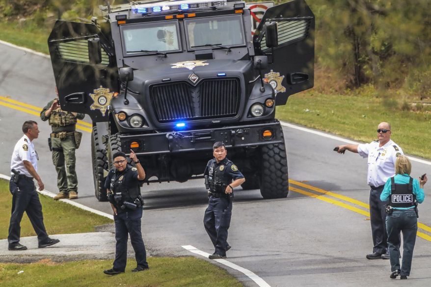 Clayton County police officers work a scene where a gunman reportedly shot a few Henry County police officers in Stockbridge, Ga., Thursday, April 4, 2019. A gunman suspected of shooting two Georgia police officers remain barricaded in a home Thursday with a teenager who was considered a hostage, police said. (John Spink/Atlanta Journal-Constitution via AP)