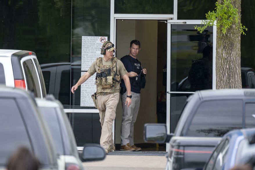In this Wednesday, April 3, 2019 photo, U.S. Immigration and Customs Enforcement officials stand outside CVE Group in Allen, Texas. Immigration agents arrested nearly 300 people at the North Texas technology company in what authorities say is one of the largest enforcement actions of its kind in a decade (Smiley N. Pool/The Dallas Morning News via AP)