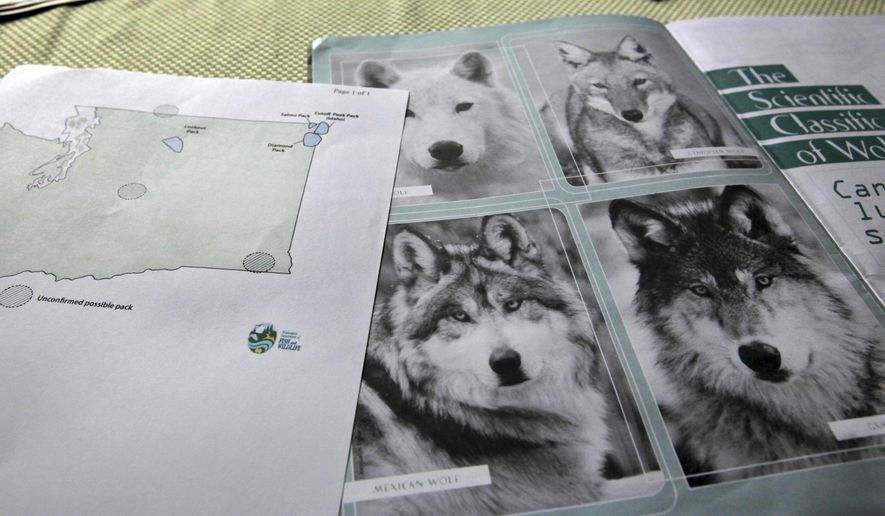 FILE - This June 18, 2011 file photo shows a map of confirmed and possible wolf packs in Washington state next to a magazine about wolves on the kitchen table of Ray Robertson, who is both both a volunteer for Conservation Northwest and a contractor for the U.S. Forest Service, near Twisp, Wash. On Thursday, April 4, 2019, the Washington Department of Fish and Wildlife said the number of gray wolves in Washington state continued to grow in 2018, and the state for the first time has documented a pack living west of the Cascade Range. (AP Photo/Elaine Thompson, File)