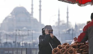 In this Thursday, April 4, 2019 photo, a woman, backdropped by the Suleymaniye mosque, buys simit, a pretzel-like snack, in Istanbul. The mood among opposition supporters in Turkey&#39;s biggest city is one of jubilation but also worry - fear that their win in Istanbul&#39;s mayoral race could be overturned in a recount taking place after the ruling party challenged the election results. (AP Photo/Lefteris Pitarakis)