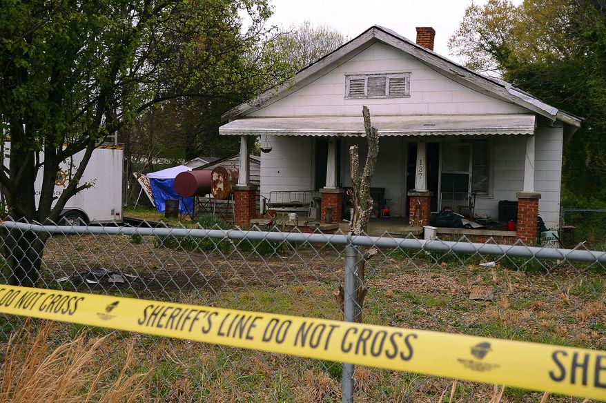 In this Friday, April 5, 2019, photo, police tape marks the area where the Spartanburg County Sheriff's Office and Spartanburg County Coroner's were working after two bodies were found buried on the property on Williams Street in Spartanburg, S.C. Two men have been charged with murder in connection with the discovery. (Tim Kimzey/Spartanburg Herald-Journal via AP)