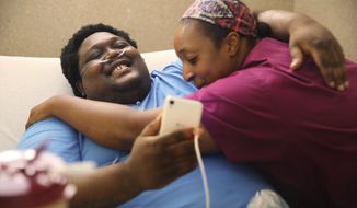 In this July 23, 2018, photo, David Green gets a hug from Minyon Donner, a certified nursing assistant at Standifer Place, before he is discharged from the facility in Chattanooga, Tenn. Green was taken home by ambulance from Standifer Place after several months of rehabilitation. It’s been almost two years since eight bullets tore through his body, shredding his spine and internal organs. His grandmother says he has nine lives. One bullet that surgeons weren’t able to remove remains lodged in his spine, leaving him paralyzed from the waist down. Green’s circumstance is not unique. He was one of 138 victims of criminal shootings in Chattanooga in 2017. (Erin O. Smith/Chattanooga Times Free Press via AP)