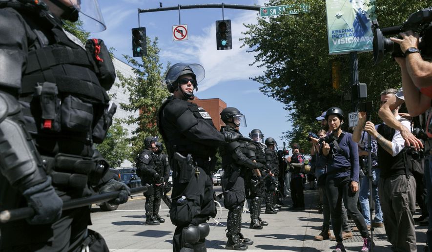 Portland police keep Patriot Prayer affiliates separate from antifa protesters during a rally in Portland, Ore., Saturday, Aug. 4, 2018. Small scuffles broke out Saturday as police in Portland, Oregon, deployed "flash bang" devices and other means to disperse hundreds of right-wing and self-described anti-fascist protesters.(AP Photo/John Rudoff)