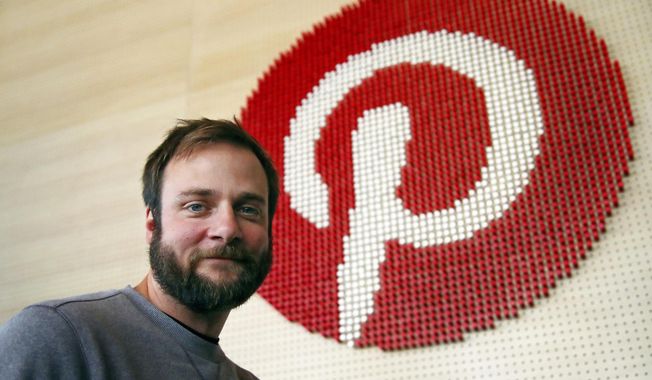 In this Oct. 11, 2018, file photo, Evan Sharp, Pinterest co-founder and chief product officer, poses for a photo beside a wall of pegs symbolizing the company logo at Pinterest headquarters in San Francisco. Pinterest plans to raise up to approximately $1.47 billion in its initial public offering. (AP Photo/Ben Margot, File)