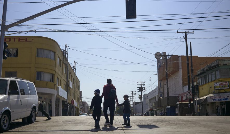 FILE - In this March 5, 2019, file photo, Ruth Aracely Monroy walks with her sons in Tijuana, Mexico. After requesting asylum in the United States, the family was returned to Tijuana to wait for their hearing in San Diego. A U.S. judge on Monday, April 8, 2019, blocked the Trump administration's policy of returning asylum seekers to Mexico as they wait for an immigration court to hear their cases but the order won't immediately go into effect. Judge Richard Seeborg in San Francisco granted a request by civil liberties groups to halt the practice while their lawsuit moves forward. He put the decision on hold until Friday, April 12 to give U.S. officials the chance to appeal. (AP Photo/Gregory Bull, File)