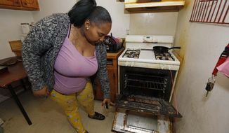 In this Feb. 20, 2019 photo, Destiny Johnson shows the broken door to her oven that she uses string to hold together, in her apartment in Cedarhurst Homes, a federally subsidized, low-income apartment complex in Natchez, Miss. The complex failed a health and safety inspection in each of the past three years. Upset with conditions, Johnson moved out in late March. (AP Photo/Rogelio V. Solis)