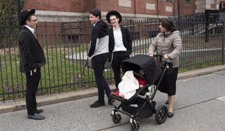 A woman, right, who identified herself as Ester, passes a group of boys, Tuesday, April 9, 2019, in the Williamsburg section of Brooklyn, New York. Ester says that she does not believe that the measles vaccination is safe. The city health department ordered all ultra-Orthodox Jewish schools in a neighborhood of Brooklyn on Monday to exclude unvaccinated students from classes during the current measles outbreak. In issuing the order, the health department said that any yeshiva in Williamsburg that does not comply will face fines and possible closure.(AP Photo/Mark Lennihan)