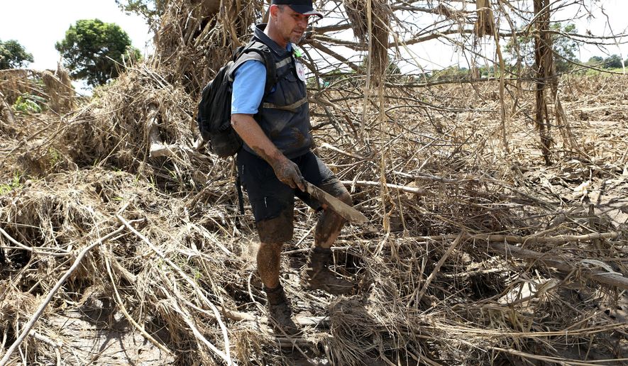 In this April, 4, 2019 photo, Stephen Fonseca, a forensics expert who tries to find and name the dead, searches for bodies in a field in Magaru, Mozambique. As the forensic coordinator for Africa with the International Committee of the Red Cross, he was the only body recovery specialist searching the rural region struck by Cyclone Idai. (AP Photo/Tsvangirayi Mukwazhi)