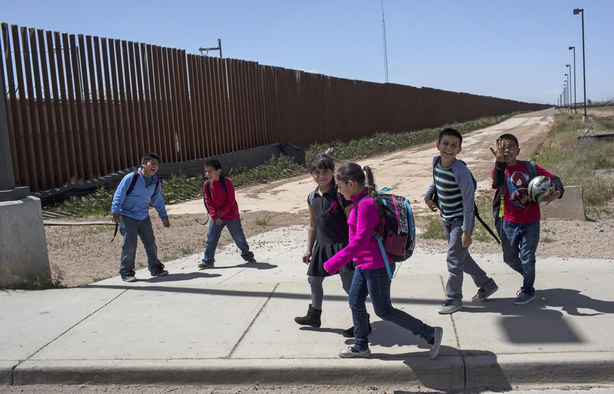 FILE - In this March 31, 2017 file photo, Columbus Elementary School students walk towards the U.S. port of entry on the border with Puerto Palomas, Mexico, after attending school in Columbus, N.M. The Army Corps of Engineers announced Wednesday, April 10, 2019, they have awarded contracts totaling nearly $1 billion for removal and replacement of vehicle fencing with pedestrian fencing along two sections of the U.S.-Mexico border. Fourty-six miles of bollard-style barrier will be installed near Columbus, N.M, and 11 miles of bollard-type barrier will be installed in a Border Patrol sector centered on Yuma, Ariz. (AP Photo/Rodrigo Abd, File)