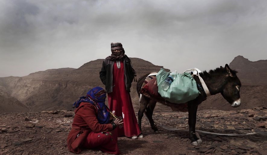 In this March 30, 2019 photo, Umm Yasser, the first Bedouin female guide from the Hamada tribe, looks at Umm Soliman as she plays the flute, near Wadi Sahw, Abu Zenima, in South Sinai, Egypt. Umm Yasser is breaking new ground among the deeply conservative Bedouin of Egypt’s Sinai Peninsula. Women among the Bedouin almost never work outside the home, and even more rarely do they interact with outsiders. But Umm Yasser is one of four women from the community who for the first time are working as tour guides. (AP Photo/Nariman El-Mofty)