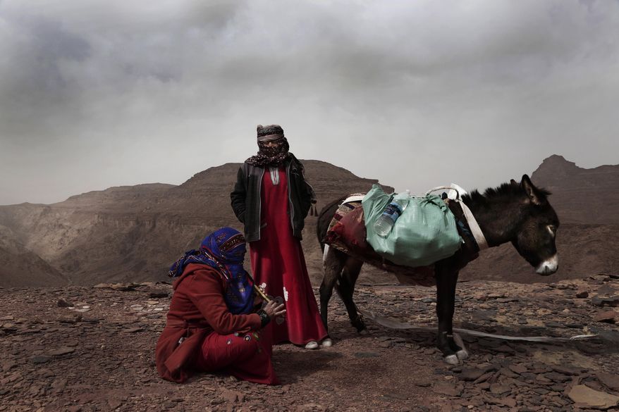 In this March 30, 2019 photo, Umm Yasser, the first Bedouin female guide from the Hamada tribe, looks at Umm Soliman as she plays the flute, near Wadi Sahw, Abu Zenima, in South Sinai, Egypt. Umm Yasser is breaking new ground among the deeply conservative Bedouin of Egypt’s Sinai Peninsula. Women among the Bedouin almost never work outside the home, and even more rarely do they interact with outsiders. But Umm Yasser is one of four women from the community who for the first time are working as tour guides. (AP Photo/Nariman El-Mofty)