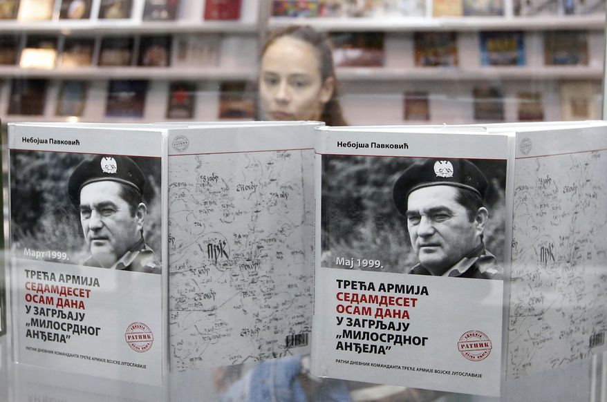 FILE - In this Saturday, Oct. 27, 2018 file photo, a girl passes by a showcase with books of former Yugoslav army chief of staff General Nebojsa Pavkovic at Belgrade's Book Fair, Serbia. Serbia's defense ministry has promoted a book by a former army chief of staff who is in jail for war crimes committed by Belgrade troops in Kosovo in the late 1990s. (AP Photo/Darko Vojinovic, File)