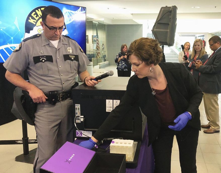 Regina Wells, center right, a forensic laboratories supervisor with Kentucky State Police, demonstrates new crime-fighting technology on Wednesday, April 10, 2019, in Frankfort, Ky. Kentucky is helping to pioneer new crime-fighting technology that allows rapid DNA testing to more quickly identify sexual assault offenders and clear those falsely accused, officials said Wednesday. (AP Photo/Bruce Schreiner)