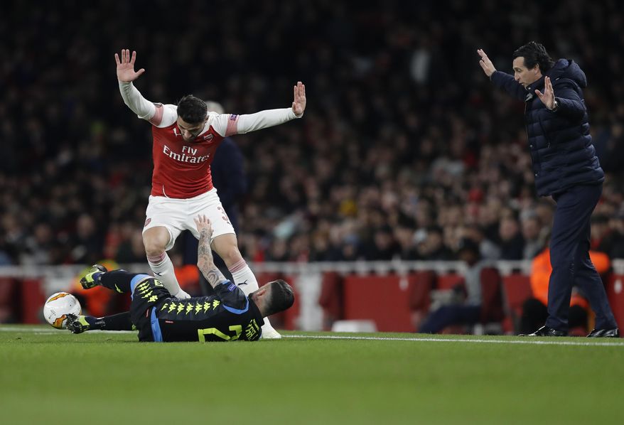 Arsenal's Sead Kolasinac, top, raises his hands, along with Arsenal's manager Unai Emery, right, after tackling Napoli's Elseid Hysaj during the Europa League first leg quarterfinal soccer match between Arsenal and Napoli at Emirates stadium in London, Thursday, April 11, 2019. (AP Photo/Kirsty Wigglesworth)