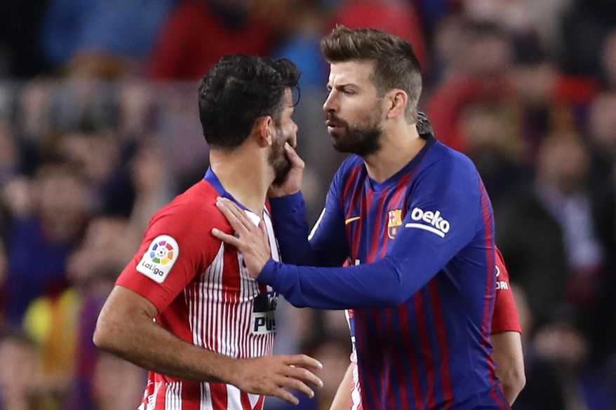 Barcelona's Gerard Pique, right, talks to Atletico forward Diego Costa as he tries to calm him after he was sent off with a red card for insulting referee Jesus Gil Manzano during a Spanish La Liga soccer match between FC Barcelona and Atletico Madrid at the Camp Nou stadium in Barcelona, Spain, Saturday April 6, 2019. (AP Photo/Manu Fernandez)