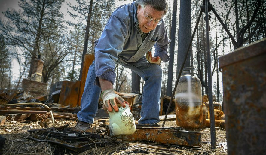 In this March 24, 2019, photo, Gene Mapa collects metal and ceramic objects that didn't burn in the Camp Fire at his house in Paradise, Calif. Mapa now lives in Colfax, which as a similar level of fire risk. A former supply hub for gold mining camps, Colfax sits a few miles from the edge of the Tahoe National Forest in the lower-elevation Sierra. It straddles Interstate 80 and serves as the last major stop between the Sacramento metropolitan area and the Lake Tahoe region. Horses graze beside deer on large ranchettes in the rugged brushy canyons along the outskirts of the city. (Hector Amezcua/The Sacramento Bee via AP)