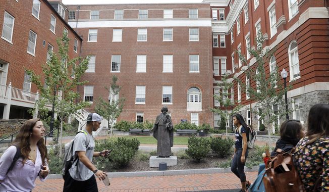 In this Sept. 1, 2016, photo, students walk past a Jesuit statue in front of Freedom Hall, center, formerly named Mulledy Hall, on the Georgetown University campus in Washington. (AP Photo/Jacquelyn Martin) **FILE**