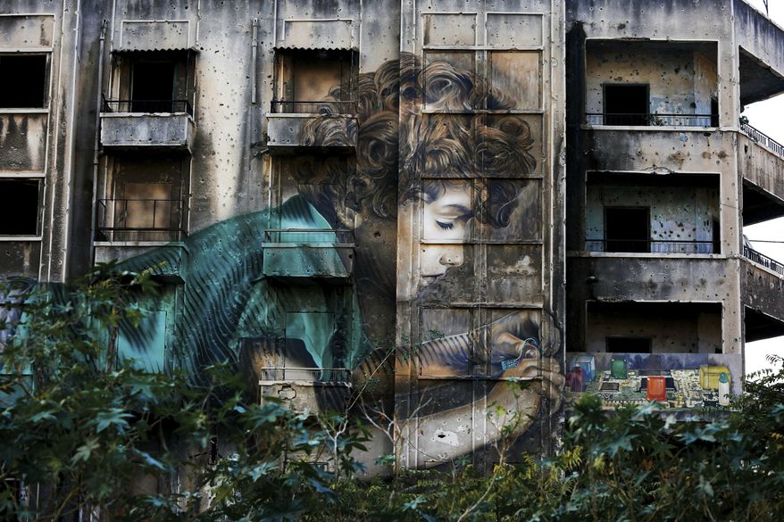 In this Nov. 12, 2018, photo, graffiti by Cuban-American artist Jorge Rodriguez-Gerada depicting a boy is painted on a bullet riddled building on the former frontline of the 1975-1990 Lebanese civil war in downtown Beirut, Lebanon. Nearly 30 years after civil war guns fell silent, dozens of bullet-scarred, shell-pocked buildings are still standing _ testimony to a brutal conflict that raged for 15 years and took the lives of 150,000 people.(AP Photo/Hassan Ammar)