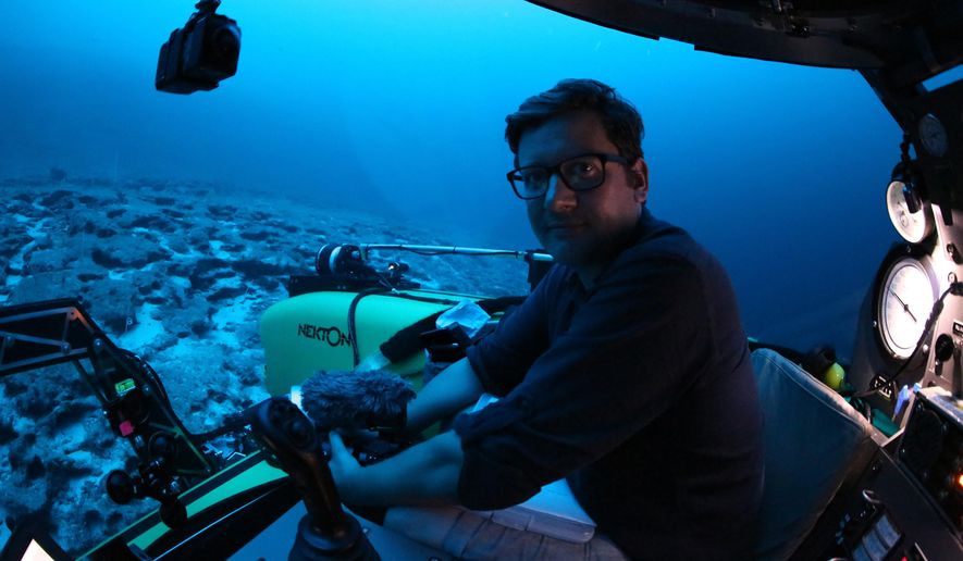 Associated Press reporter, David Keyton poses for a photograph inside a submersible at around 400 feet below the surface off the coast of the island of St. Joseph in the Seychelles, Monday April 8, 2019. Able to operate down to 1,000 feet, these manned submersibles give scientists a unique understanding of changes in habitats as sunlight diminishes through the different layers of ocean. (AP Photo/Robert Carmichael)