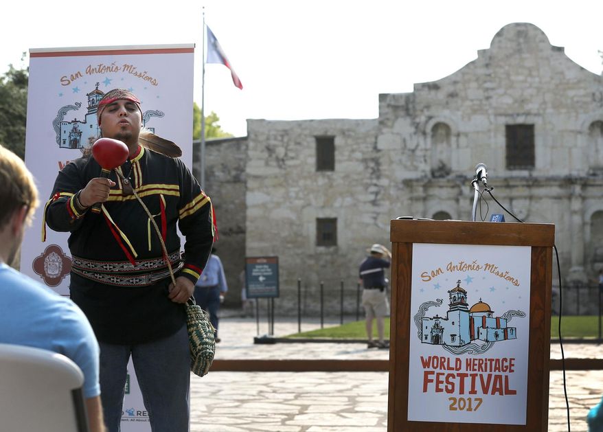 In this Sept. 6, 2017 photo, Ramon Vasquez, left, with American Indians in Texas at the Spanish Colonial Missions, sings during an announcement made in front of the Alamo in San Antonio, regarding the kickoff of the second Annual World Heritage Festival. Two competing requests to designate the Alamo in San Antonio as a Historical Texas Cemetery could change how the mission is remembered. The Texas General Land Office wants to have the Alamo church listed as a historic Texas cemetery, citing the names of three people buried there nearly a century before the 1836 battle. Another proposal from Native American groups seeks a much larger area be designated a cemetery at the revered site.(John Davenport/The San Antonio Express-News via AP)