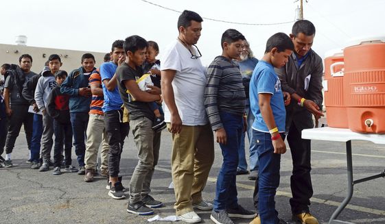 In this Friday, April 12, 2019 photo, migrants wait in line to get drinks after being dropped off by the Border Patrol at the Gospel Rescue Mission in Las Cruces, N.M. The U.S. Border Patrol agents dropped off asylum-seeking migrants in New Mexico&#39;s second most populous city for the second day in a row Saturday, April 13, 2019 prompting Las Cruces city officials to appeal for donations of food and personal hygiene items. The migrants were being temporarily housed at a homeless shelter, a city recreation center and a campus of social service agencies. (Blake Gumprecht/The Las Cruces Sun News via AP)