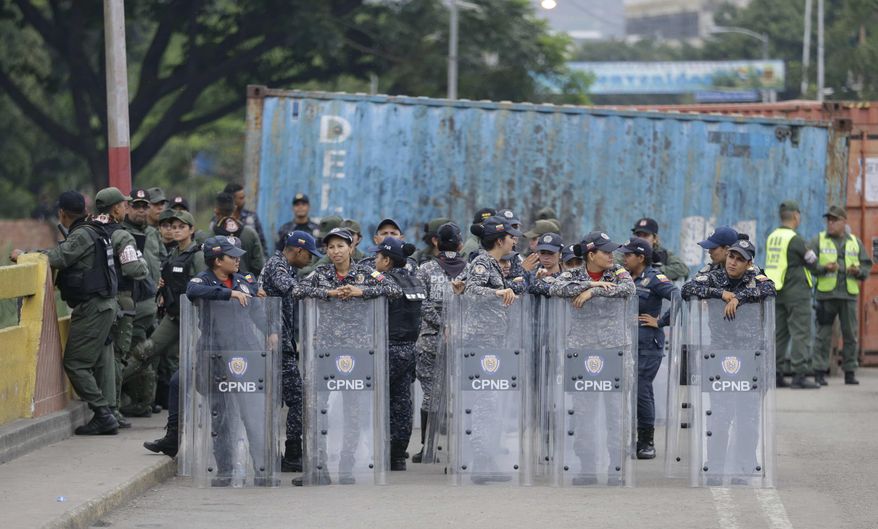 Female Venezuelan soldiers stand behind their shields on the Simon Bolivar International Bridge, where cargo trailers block it, seen from La Parada near Cucuta, Colombia, on the border with Venezuela, Sunday, April 14, 2019. Venezuelan authorities have limited the use of the bridge to students, seniors and the sick. U.S. Secretary of State Mike Pompeo is on a four-day Latin American tour, making his final stop at the Colombian border to meet with representatives of Venezuelan refugees. (AP Photo/Fernando Vergara)
