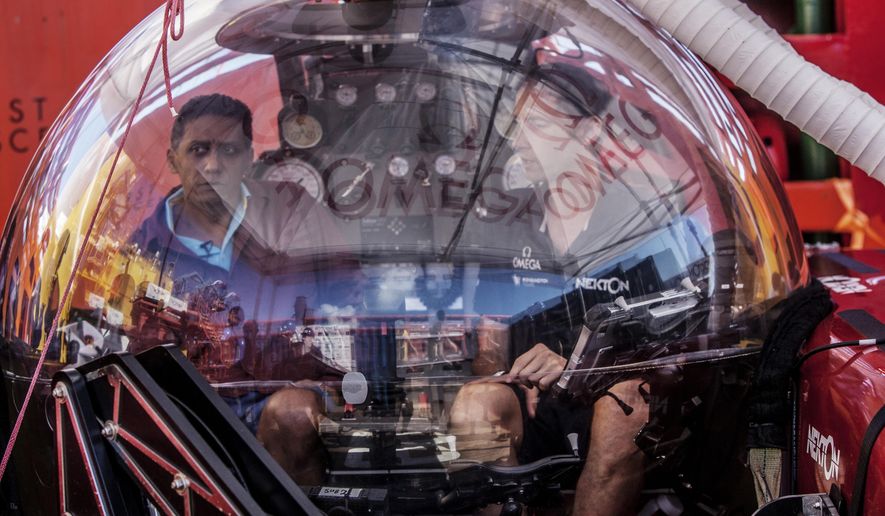 In this Saturday, April 13, 2019, photo, Seychelles President Danny Faure, left, sits inside a submersible on the deck of vessel Ocean Zephyr, off the coast of Desroches, in the outer islands of Seychelles. Faure toured the vessel and was presented with some of the findings and observations made by a British-led science expedition documenting changes taking place beneath the waves that could affect billions of people in the surrounding region over the coming decades. (AP Photo/Steve Barker)