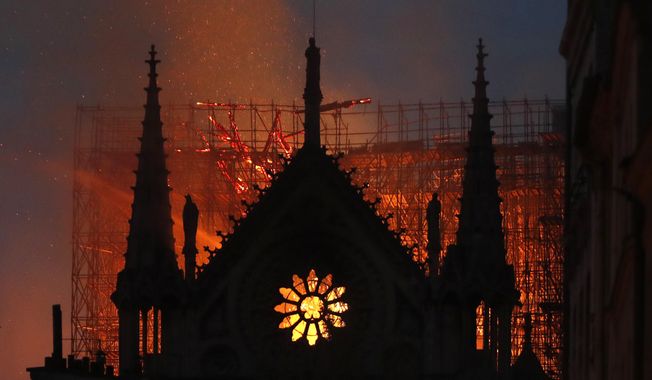 Flames and smoke rise from Notre Dame cathedral as it burns in Paris, Monday, April 15, 2019. Massive plumes of yellow brown smoke is filling the air above Notre Dame Cathedral and ash is falling on tourists and others around the island that marks the center of Paris. (AP Photo/Thibault Camus)