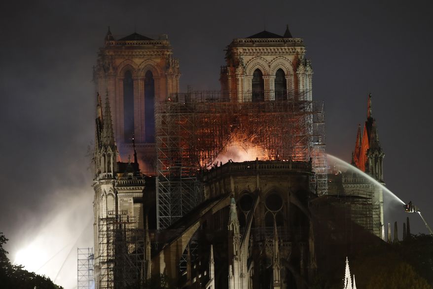 People watch Notre Dame cathedral burning in Paris, Monday, April 15, 2019. A catastrophic fire engulfed the upper reaches of Paris' soaring Notre Dame Cathedral as it was undergoing renovations Monday, threatening one of the greatest architectural treasures of the Western world as tourists and Parisians looked on aghast from the streets below. (AP Photo/Christophe Ena)