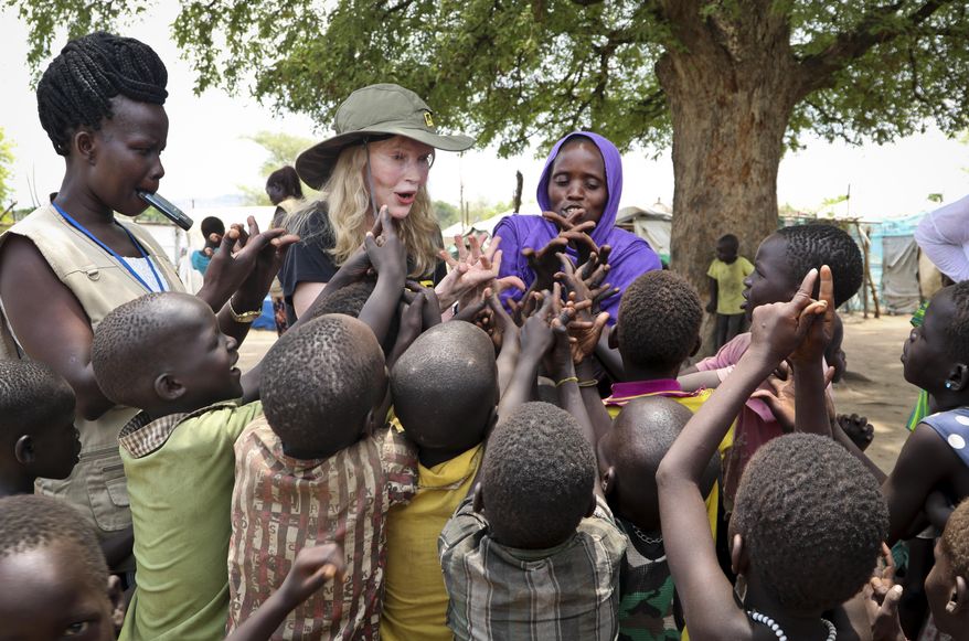 In this photo taken Tuesday, April 2, 2019, human rights activist Mia Farrow, center-left, plays a game with children during a visit to an internally displaced person's camp in the capital Juba, South Sudan. (AP Photo/Sam Mednick)