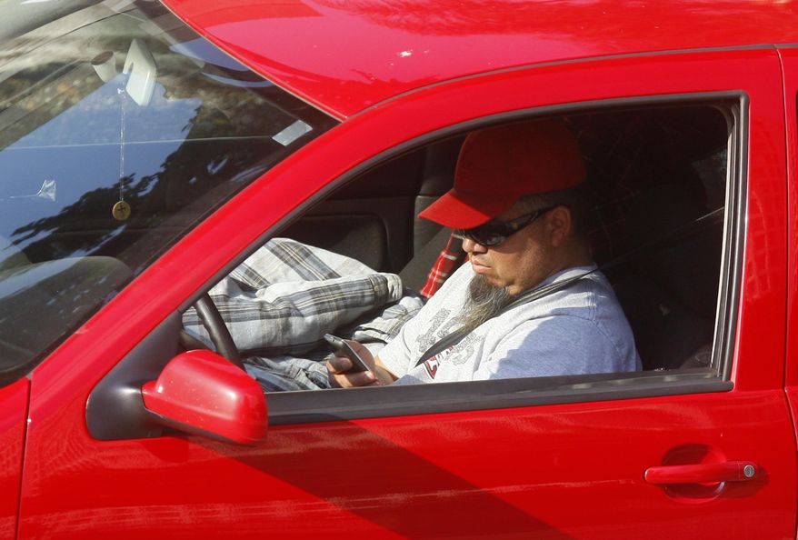 FILE - In this Dec. 14, 2011 file photo, a driver uses a cellphone while driving in Los Angeles. Arizona is one of just three states that has no statewide ban on texting while driving, but that could change this year after a decade of failed attempts in the Legislature to outlaw it. The death of a police officer struck by a driver last Jan. 8, 2019, who was allegedly texting may be a catalyst for lawmakers to change the law. The Senate has passed three bills to punish distracted drivers, but they're held up in the House amid a disagreement among Republicans about how far to go in legislating behavior. (AP Photo/Damian Dovarganes, File)