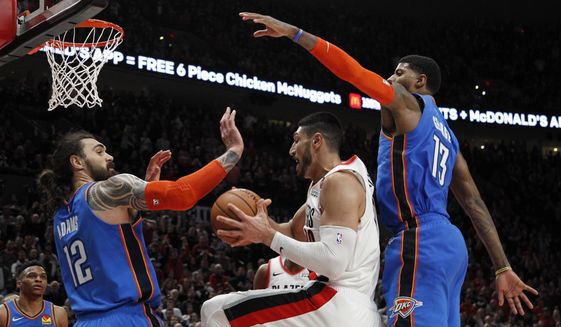 Portland Trail Blazers center Enes Kanter, center, grabs a rebound as Oklahoma City Thunder center Steven Adams, front left, and Thunder forward Paul George, right, defend during the second half of Game 1 of a first-round NBA basketball playoff series in Portland, Ore., Sunday, April 14, 2019. (AP Photo/Steve Dipaola)