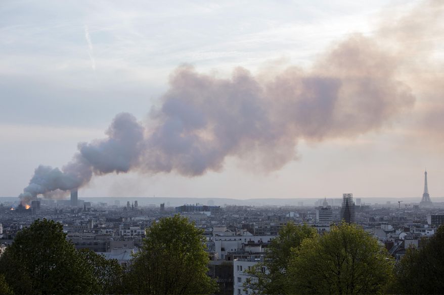 Smoke fill the air as Notre Dame cathedral is burning in Paris, Monday, April 15, 2019. Massive plumes of yellow brown smoke is filling the air above Notre Dame Cathedral and ash is falling on tourists and others around the island that marks the center of Paris. (AP Photo/Rafael Yaghobzadeh)