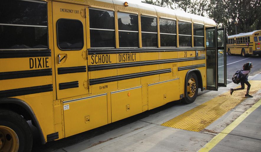 FILE - In this Oct. 18, 2018 file photo, a student hops off the school bus at Dixie Elementary School in San Rafael, Calif. The Dixie School District board in the California city of San Rafael plans to vote on whether to keep its name, which critics say it is linked to the Confederacy and slavery and supporters maintain is it named after a Native American woman. (Gabrielle Lurie/San Francisco Chronicle via AP, File)